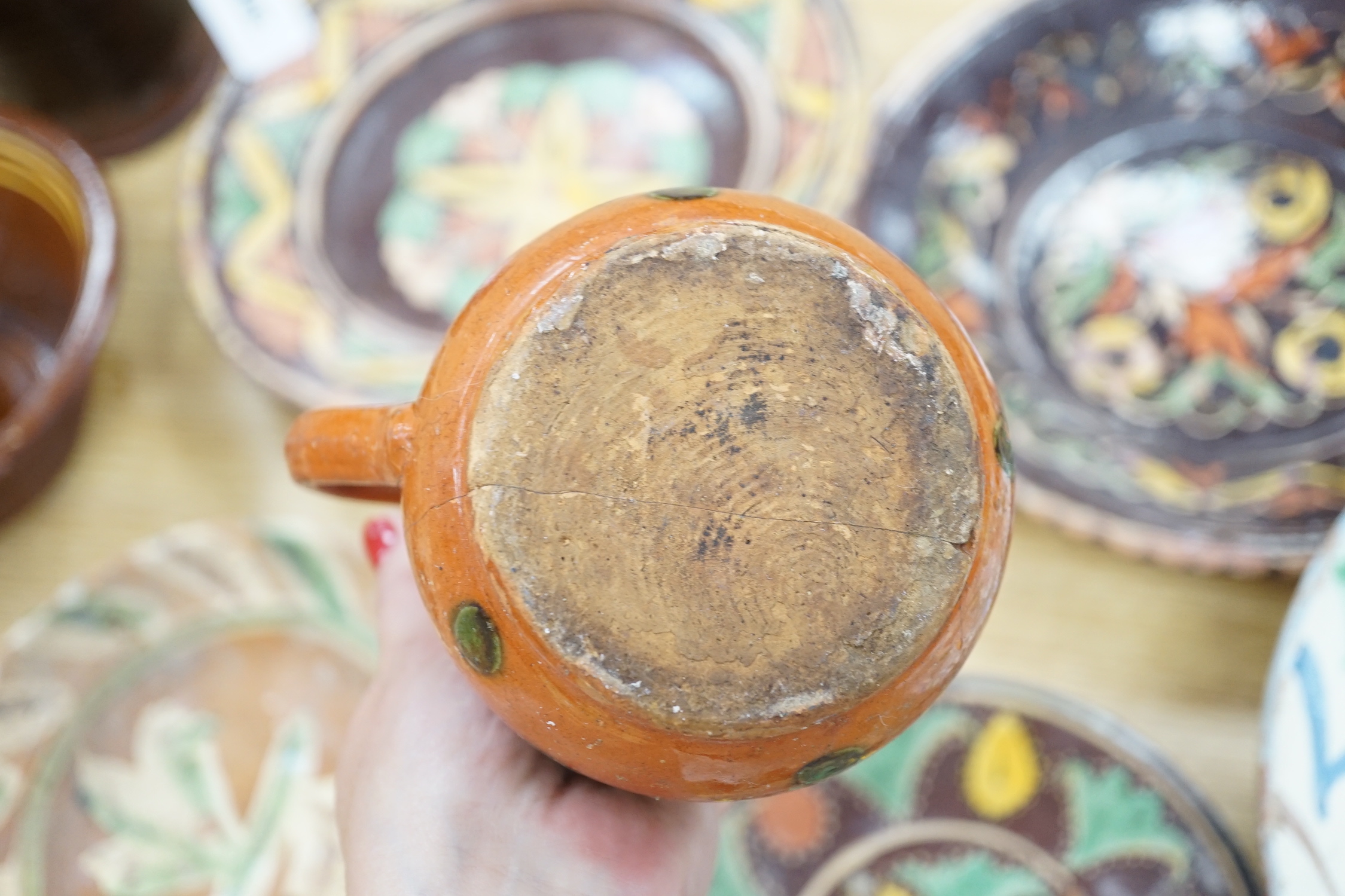 A group of Mediterranean slipware dishes, bowls and jugs, decorated in colours on a predominantly brown or ochre ground, the largest 33cm in diameter